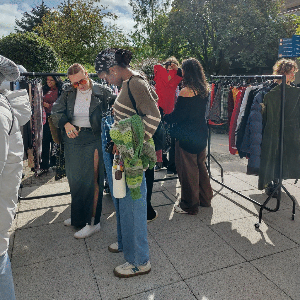 Students at UEA Welcome market looking at rails and trying on jeans.