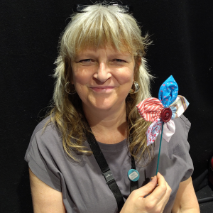 A community connector posing with a colourful fabric flower she has just made.