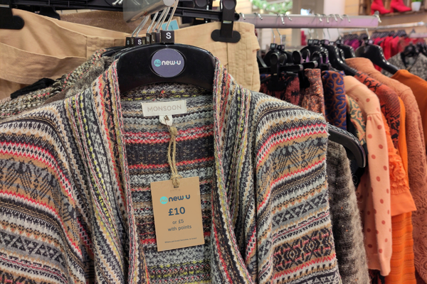 Monsoon cardigan hanging on a clothing rail with orange tops in the background